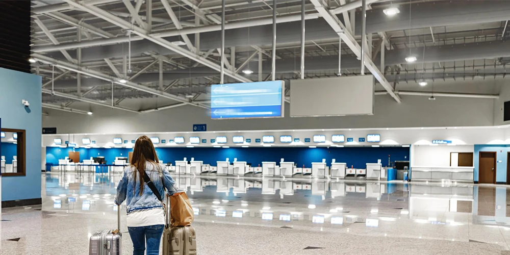 a women walking a airport terminal with suicates and the ceiling is brighter