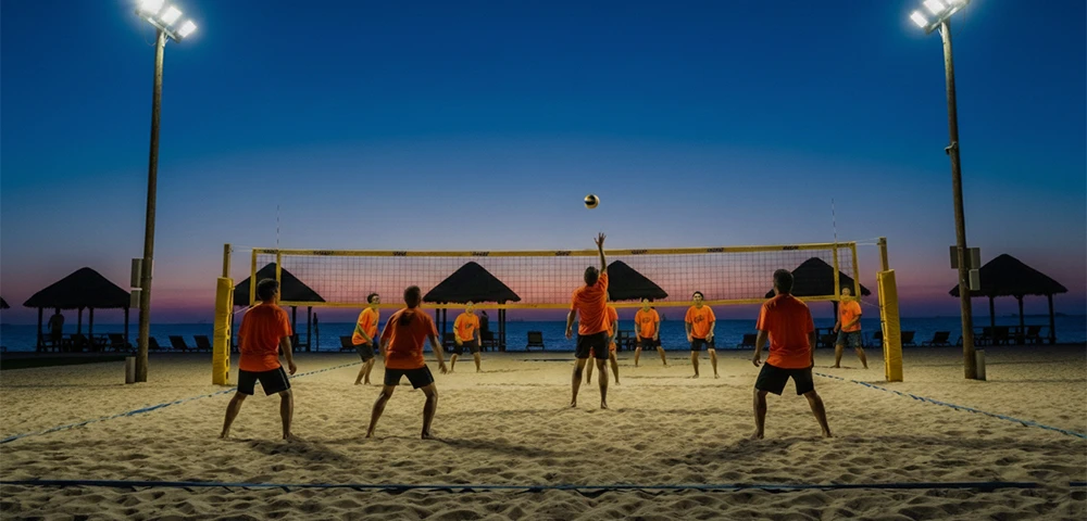 people play sandy beach volleyball at night