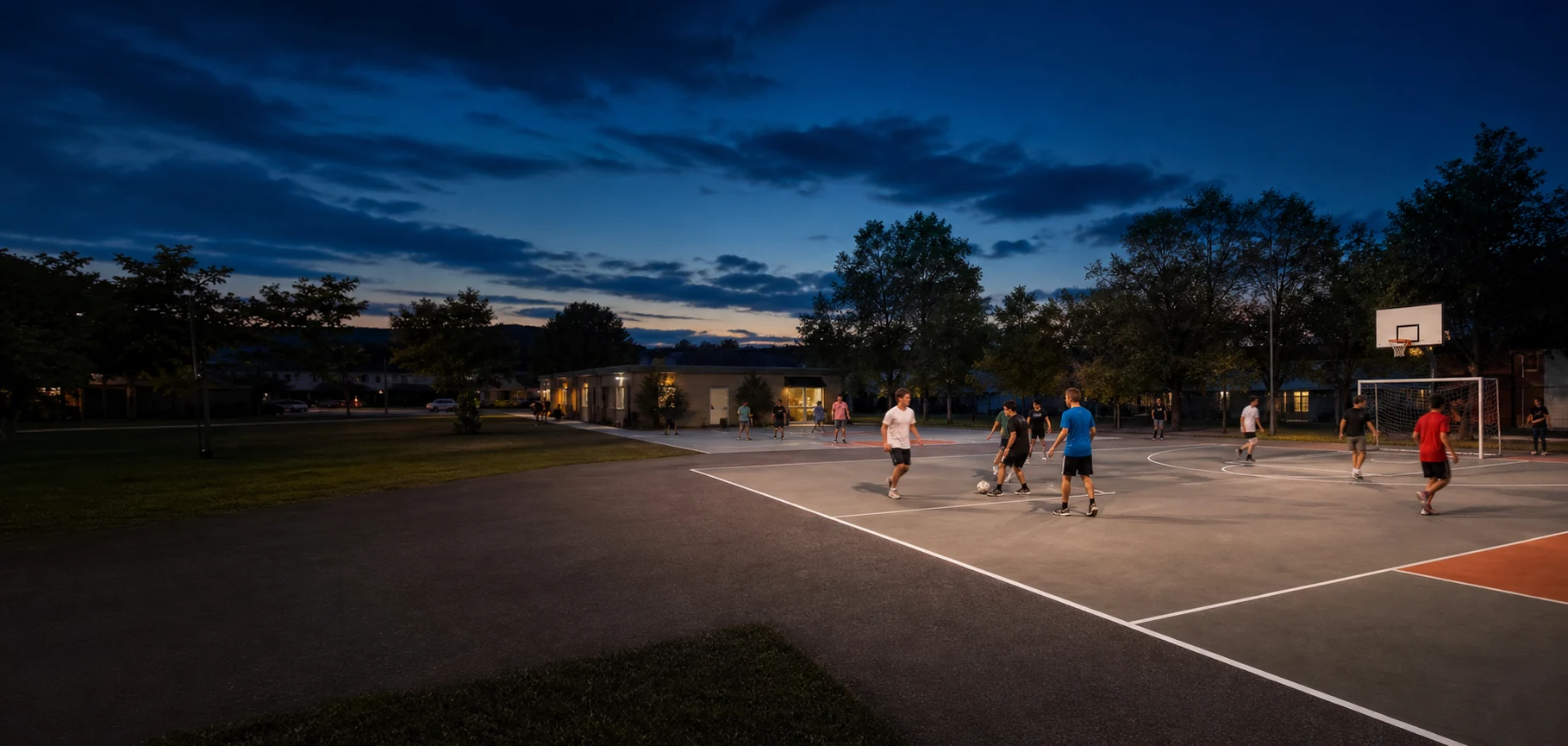 Residents playing on a well-lit community multi-sport court at dusk